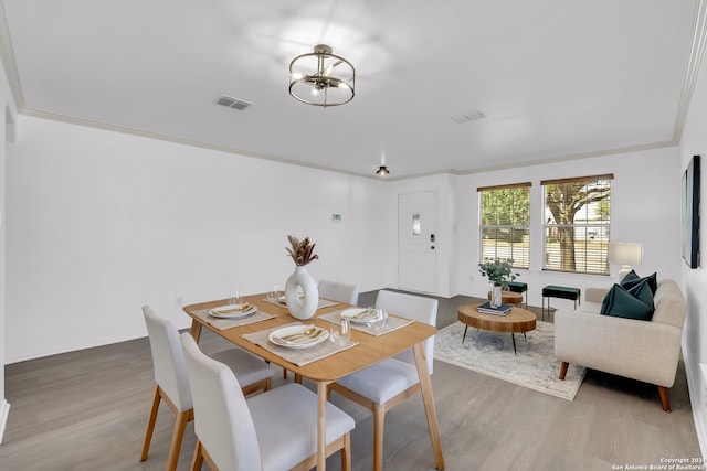 dining room with wood-type flooring, a notable chandelier, and ornamental molding