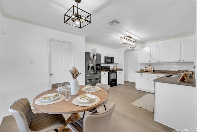 dining space featuring a chandelier, ornamental molding, sink, and light hardwood / wood-style flooring