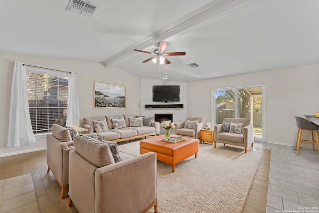 living room featuring a brick fireplace, vaulted ceiling with beams, light hardwood / wood-style flooring, and ceiling fan