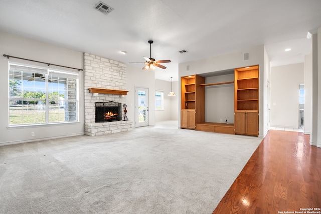 unfurnished living room featuring a stone fireplace, ceiling fan, and light wood-type flooring