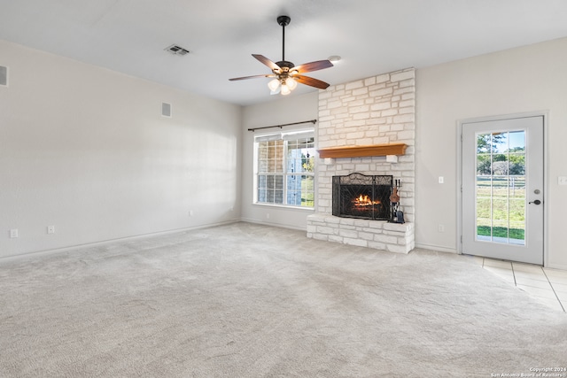 unfurnished living room featuring ceiling fan, a fireplace, and light colored carpet