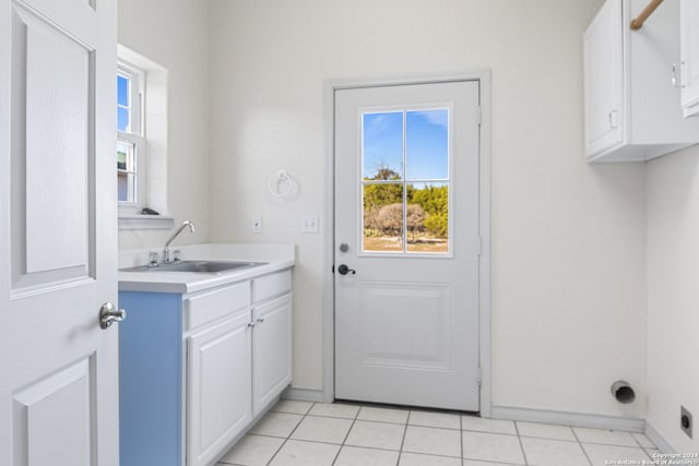 laundry room with sink, light tile patterned flooring, and cabinets