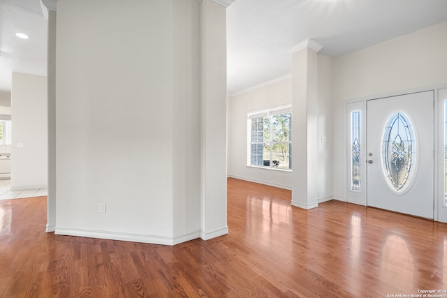 foyer with light wood-type flooring and crown molding