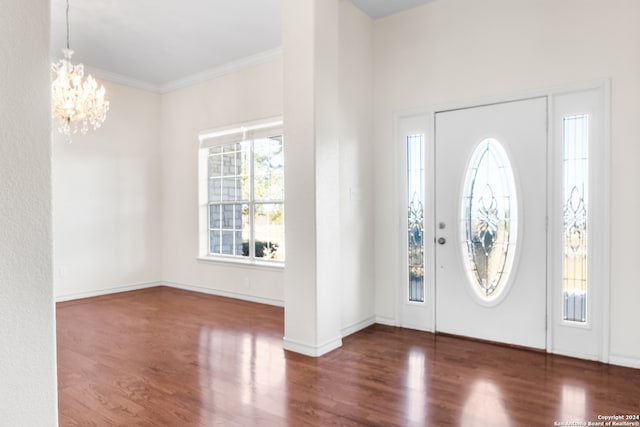 entryway with dark hardwood / wood-style flooring, an inviting chandelier, and ornamental molding