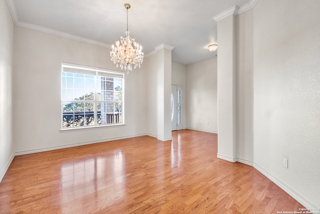 spare room featuring crown molding, light hardwood / wood-style flooring, and a chandelier