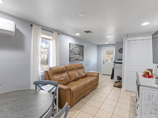 living room featuring a wall mounted AC, light tile patterned floors, and a textured ceiling