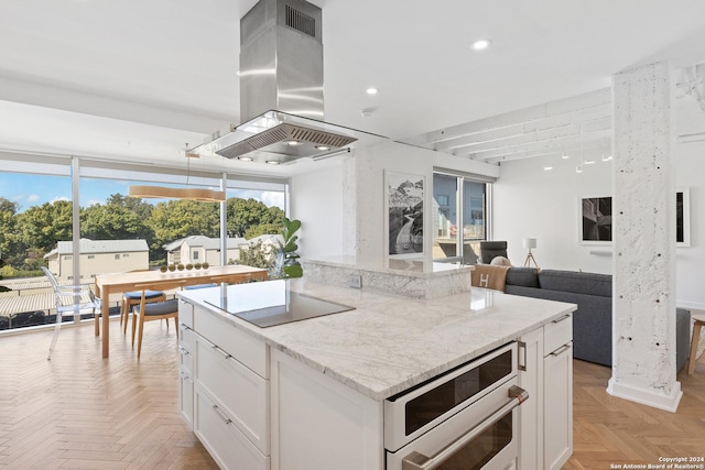 kitchen with black electric stovetop, light stone counters, recessed lighting, white cabinets, and island exhaust hood