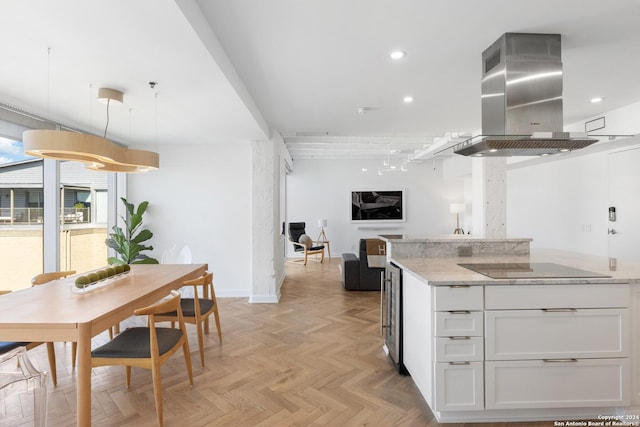 kitchen with light stone countertops, island exhaust hood, black electric cooktop, white cabinetry, and recessed lighting