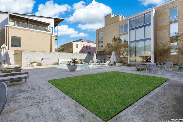 view of home's community with a patio area, fence, a pool, and a lawn