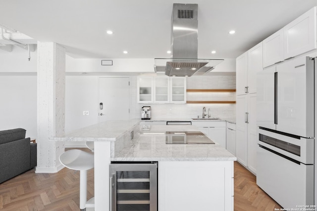 kitchen with wine cooler, white cabinets, freestanding refrigerator, island exhaust hood, and glass insert cabinets