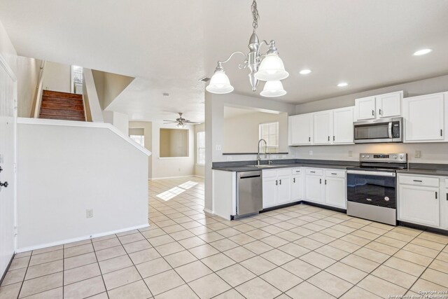 kitchen with sink, pendant lighting, white cabinets, ceiling fan with notable chandelier, and appliances with stainless steel finishes