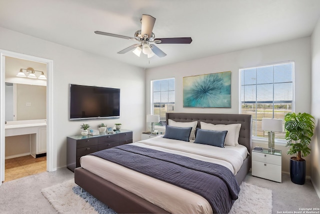 bedroom with light carpet, ensuite bathroom, and ceiling fan