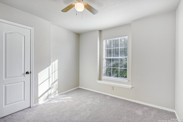 spare room featuring light carpet, ceiling fan, and a textured ceiling