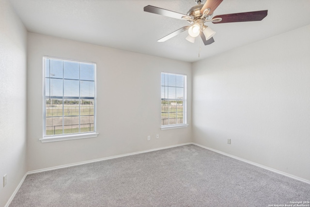 carpeted spare room featuring plenty of natural light and ceiling fan