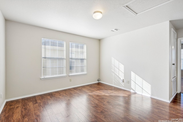 empty room with a textured ceiling and dark wood-type flooring