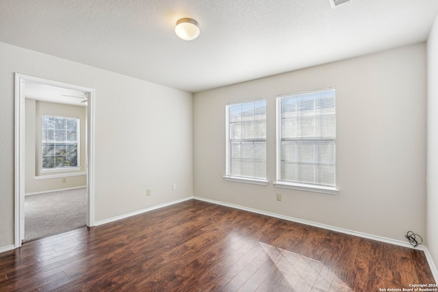 unfurnished room with dark wood-type flooring and a textured ceiling