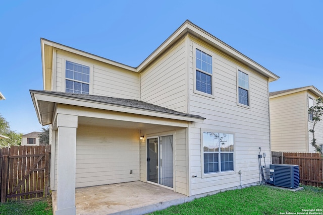 rear view of property with central AC unit, a patio area, and a lawn