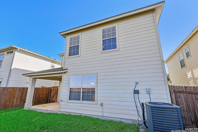 back of property with a patio, central AC unit, and a lawn