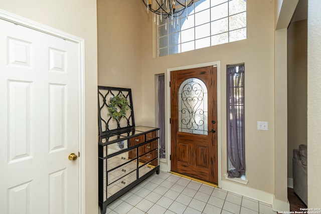 tiled foyer featuring a towering ceiling and a notable chandelier