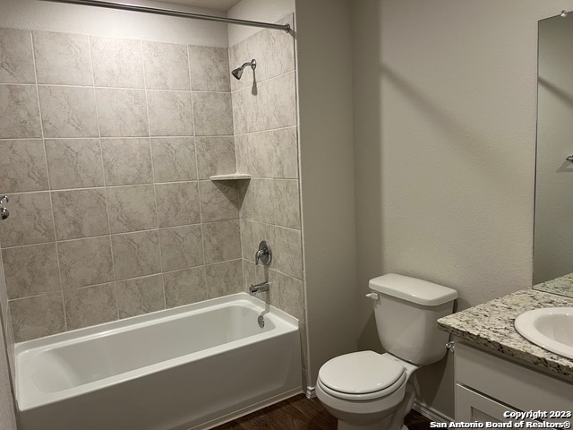 full bathroom featuring hardwood / wood-style floors, vanity, toilet, and tiled shower / bath