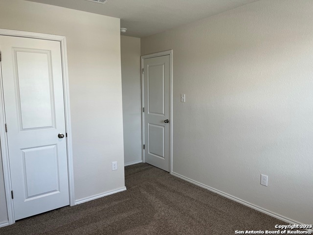 unfurnished bedroom with dark carpet