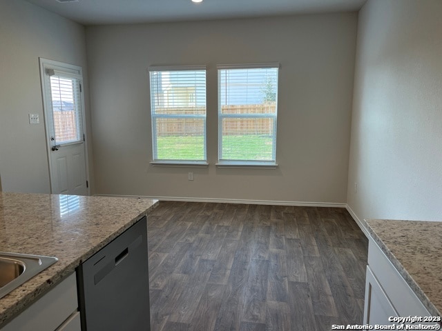 kitchen featuring light stone countertops, dark wood-type flooring, white cabinets, and stainless steel dishwasher