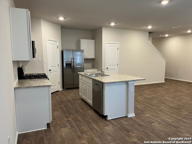 kitchen with white cabinetry, sink, dark wood-type flooring, stainless steel appliances, and a center island with sink