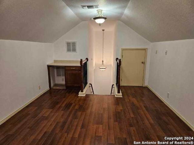 bonus room with a textured ceiling, dark hardwood / wood-style floors, and vaulted ceiling