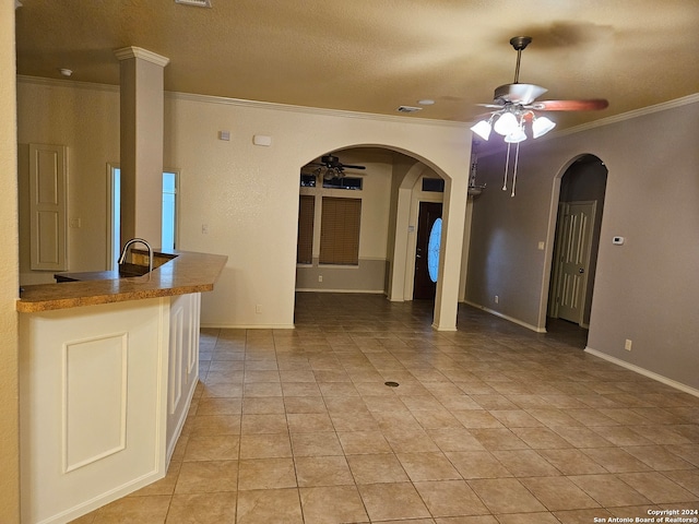 tiled empty room featuring a textured ceiling, ceiling fan, and crown molding