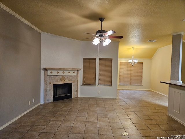 unfurnished living room featuring a tile fireplace, a textured ceiling, light tile patterned floors, ceiling fan with notable chandelier, and ornamental molding