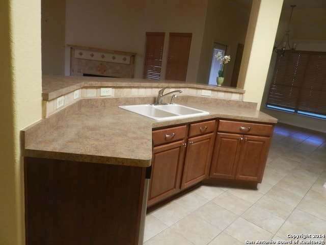 kitchen featuring light tile patterned flooring, kitchen peninsula, and sink