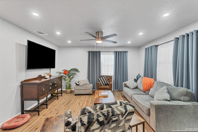 living room with ceiling fan, light hardwood / wood-style floors, and a textured ceiling