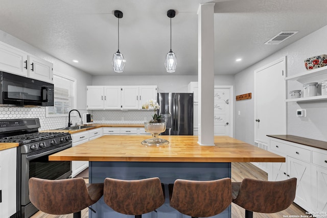 kitchen with butcher block countertops, white cabinetry, and black appliances