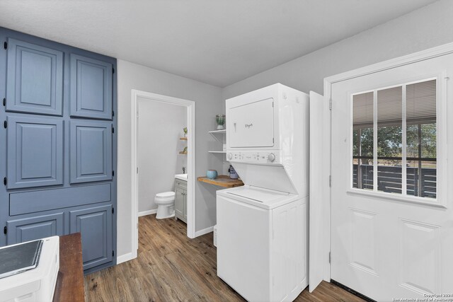 laundry area with dark wood-type flooring and stacked washer and clothes dryer