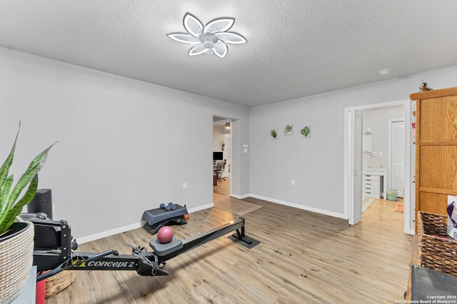 workout area featuring ceiling fan, wood-type flooring, and a textured ceiling