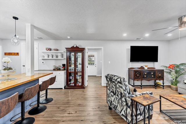 living room featuring wood-type flooring, a textured ceiling, and ceiling fan