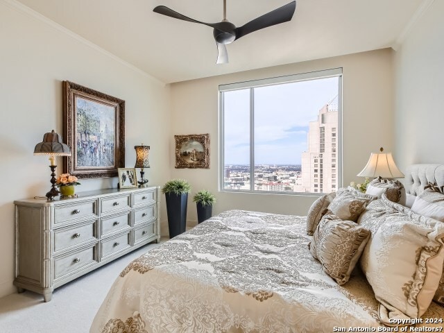 bedroom with ceiling fan, light colored carpet, and ornamental molding