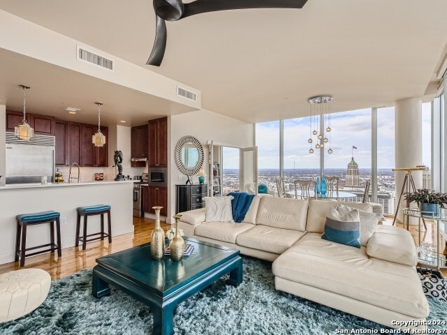 living room with sink, plenty of natural light, an inviting chandelier, and light hardwood / wood-style flooring