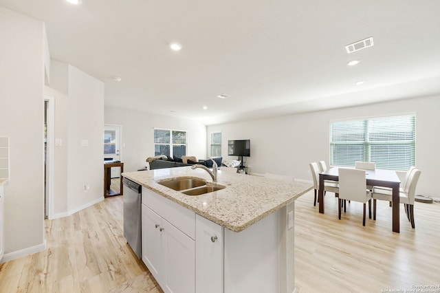 kitchen with white cabinetry, dishwasher, sink, light hardwood / wood-style flooring, and a center island with sink