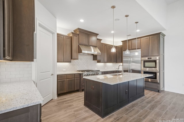 kitchen featuring decorative light fixtures, sink, decorative backsplash, light stone counters, and stainless steel appliances