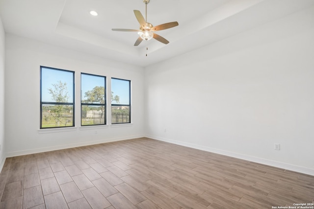 unfurnished room featuring a raised ceiling and ceiling fan