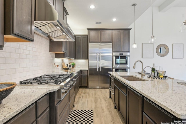23422 Grande Vis, San Antonio, TX 78261 - kitchen featuring appliances with stainless steel finishes, exhaust hood, a sink, dark brown cabinetry, and light stone counters