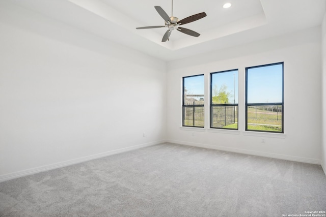 carpeted empty room featuring a raised ceiling and ceiling fan