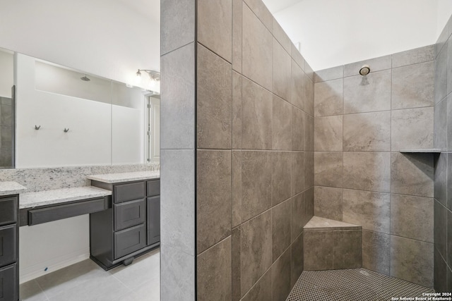 bathroom with tile patterned floors, vanity, and a tile shower