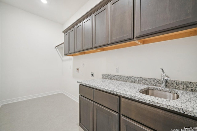 kitchen featuring dark brown cabinetry, light stone countertops, and sink