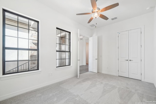 unfurnished bedroom with light colored carpet, ceiling fan, and a closet