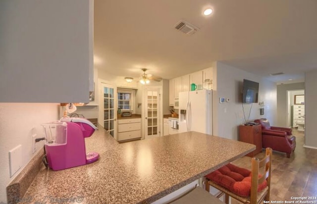 kitchen with white appliances, kitchen peninsula, ceiling fan, dark hardwood / wood-style flooring, and white cabinetry