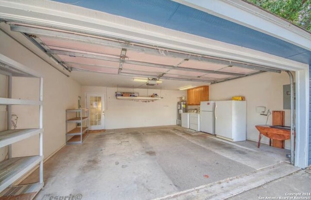 garage featuring white refrigerator, a garage door opener, and washing machine and clothes dryer