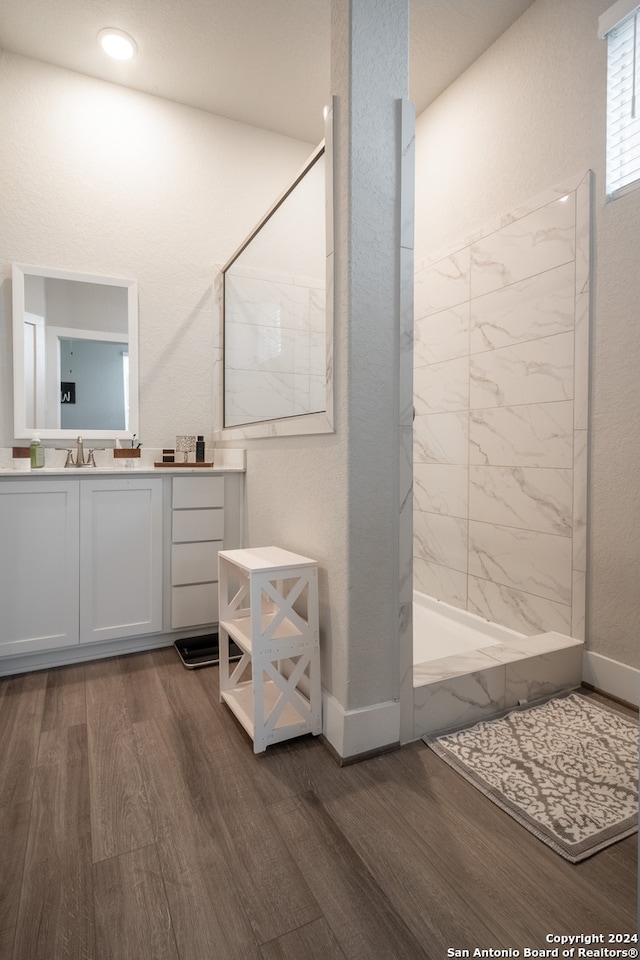 bathroom with tiled shower, vanity, and hardwood / wood-style flooring