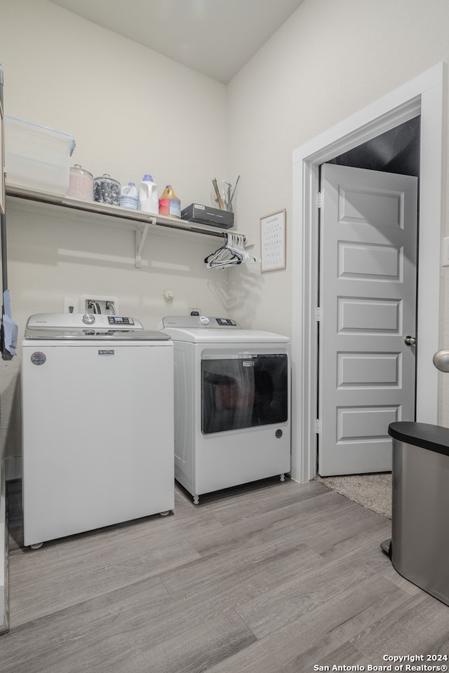 laundry room featuring separate washer and dryer and light hardwood / wood-style flooring